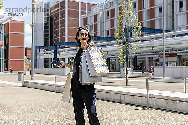 Frau schaut weg  während sie mit Einkaufstüten in der Stadt steht
