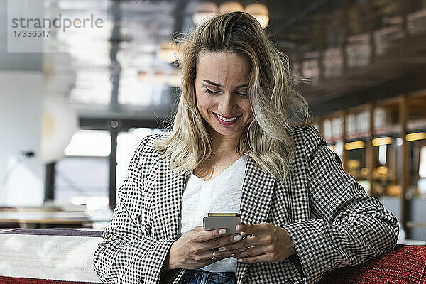 Lächelnde Geschäftsfrau mit Mobiltelefon in einem Café