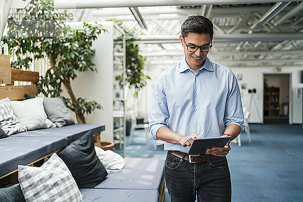 Geschäftsmann mit Brille benutzt digitales Tablet im Büro