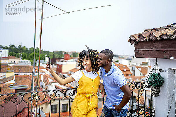 Lächelnder Mann und Frau nehmen Selfie durch Smartphone in Balkon