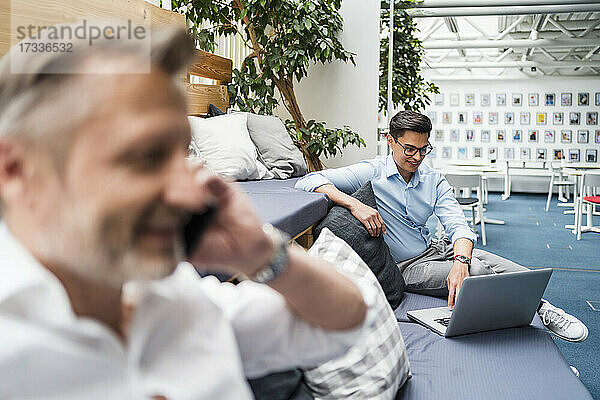 Männlicher Berufstätiger mit Laptop bei der Arbeit im Büro