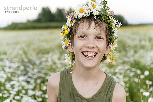 Junge mit Blumentiara lächelnd im Feld