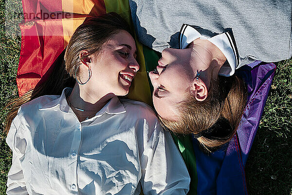 Lesbisches Paar  das sich auf der Regenbogenfahne liegend ansieht