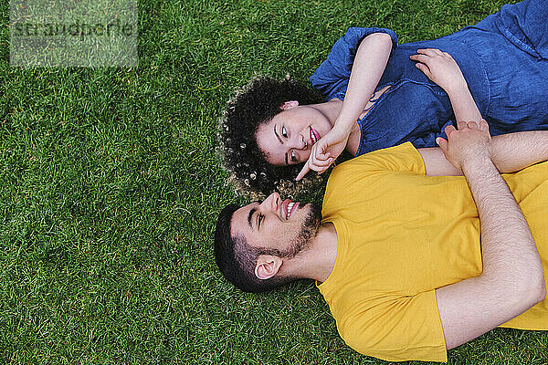 Junge Frau mit Freund im Gras liegend im Park