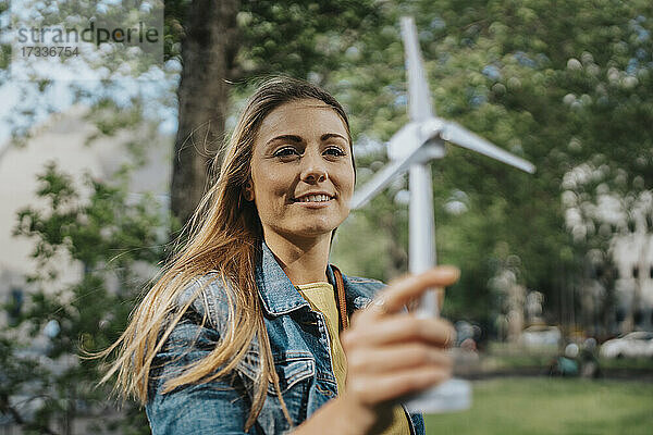 Junge Frau betrachtet das Modell einer Windkraftanlage