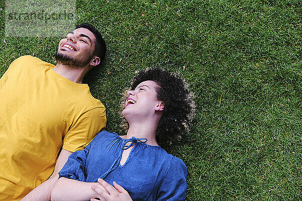 Glückliches junges Paar  das zusammen auf dem Rasen eines Parks liegt