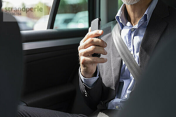 Geschäftsmann hält Smartphone im Auto