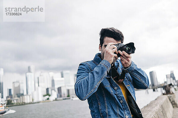Mann beim Fotografieren mit Kamera an der Promenade