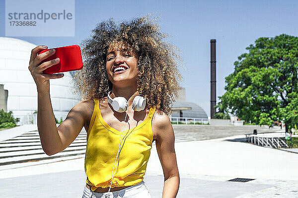 Glückliche junge Frau bei einem Videogespräch über ihr Smartphone an einem sonnigen Tag