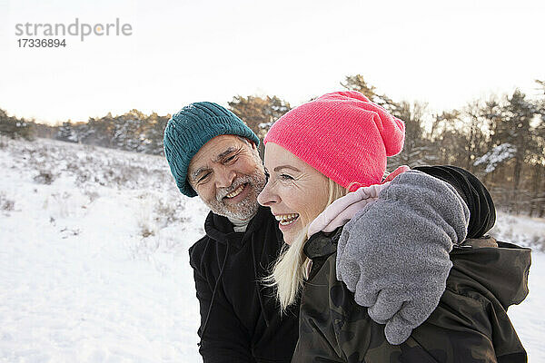 Lächelnder Mann mit Arm um Frau im Winter
