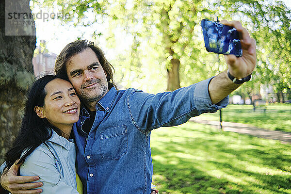 Mann macht Selfie mit Frau durch Handy in öffentlichem Park