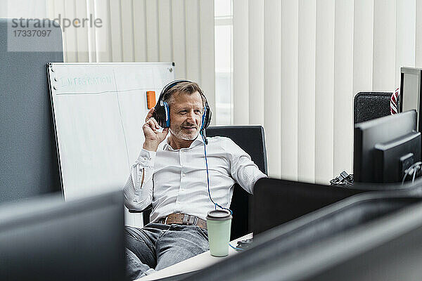 Lächelnde männliche Fachkraft mit Headset bei der Arbeit im Büro