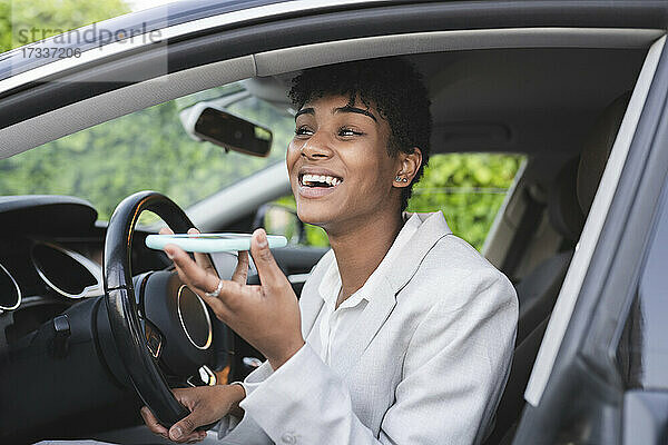 Geschäftsfrau sendet Sprachnachrichten über ihr Smartphone  während sie im Auto sitzt