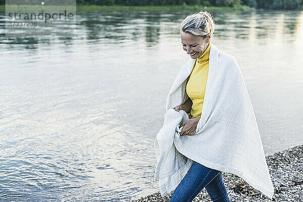 Lächelnde Frau mit Decke am Flussufer