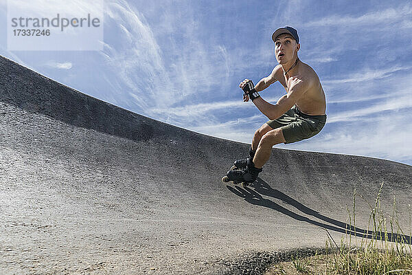 Hemdloser junger Mann beim Rollschuhlaufen im Skateboardpark