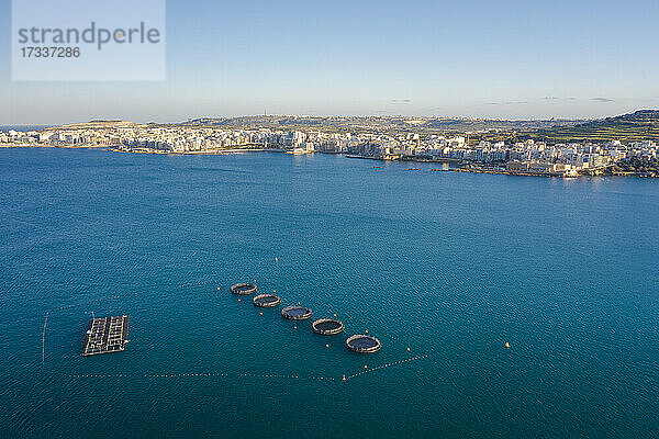 Malta  Northern District  Saint Pauls Bay  Luftaufnahme einer Fischzucht mit Küstenstadt im Hintergrund
