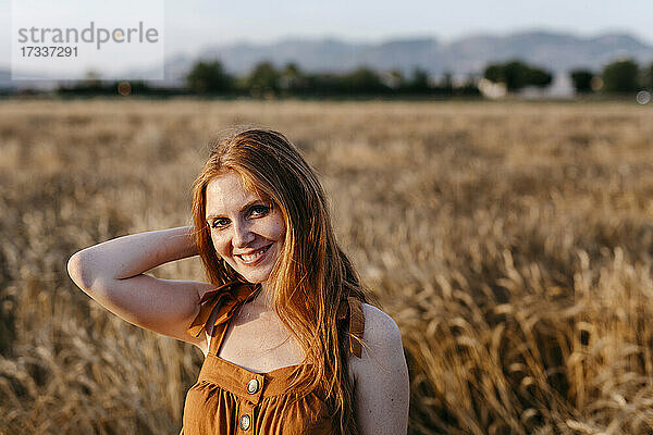 Lächelnde rothaarige Frau auf einem landwirtschaftlichen Feld