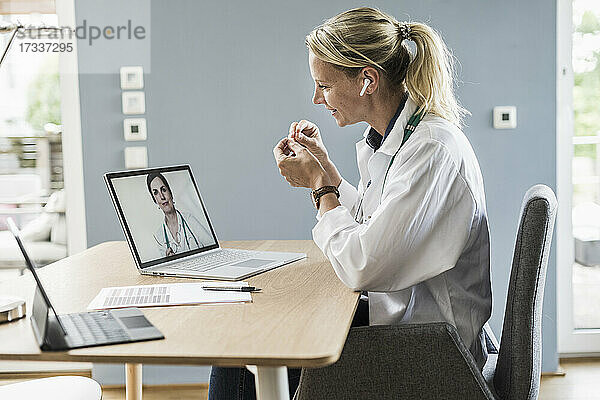 Weibliche Fachkraft gestikuliert  während sie mit einem Kollegen über einen Videoanruf am Laptop im Büro diskutiert