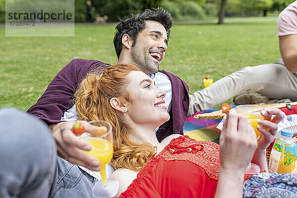 Glückliche Freunde mit Getränk beim Picknick im Park