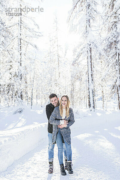 Glückliches Paar  das sich im Urlaub im Schnee umarmt