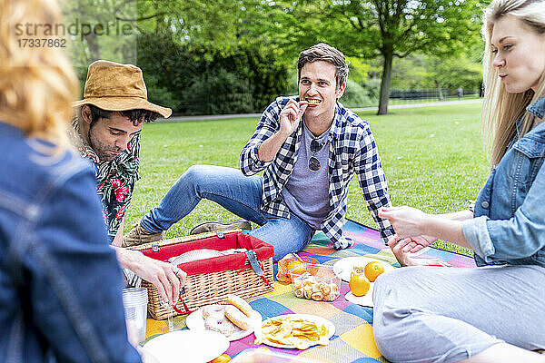 Freunde essen auf einer Picknickdecke sitzend