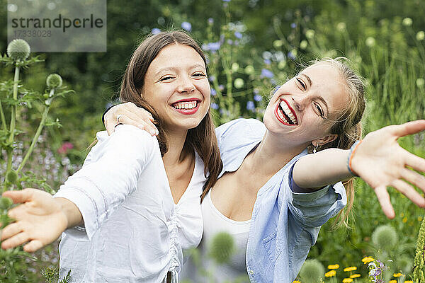 Fröhliche Frauen gestikulieren bei einer Umarmung in der Natur