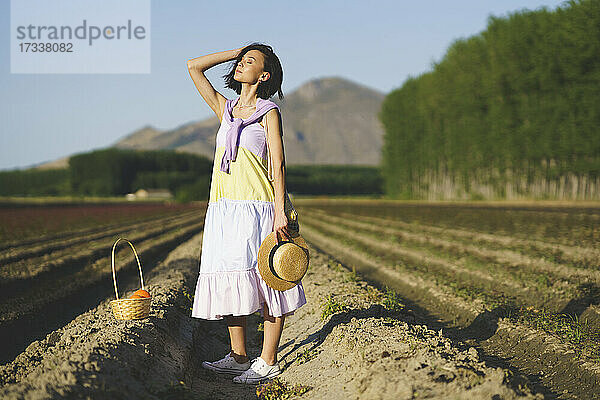 Junge Frau mit geschlossenen Augen auf einem landwirtschaftlichen Feld bei Sonnenuntergang