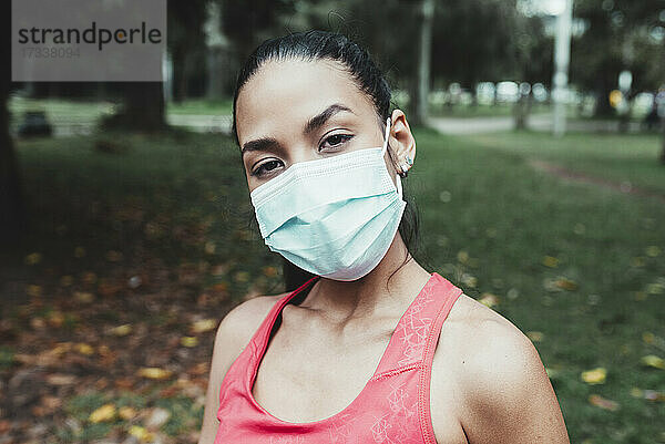 Weibliche Athletin trägt während der Pandemie eine Gesichtsmaske in einem öffentlichen Park