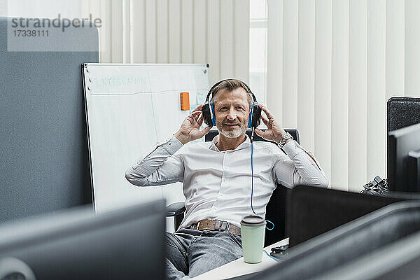 Lächelnder Geschäftsmann  der ein Headset trägt  während er im Büro sitzt
