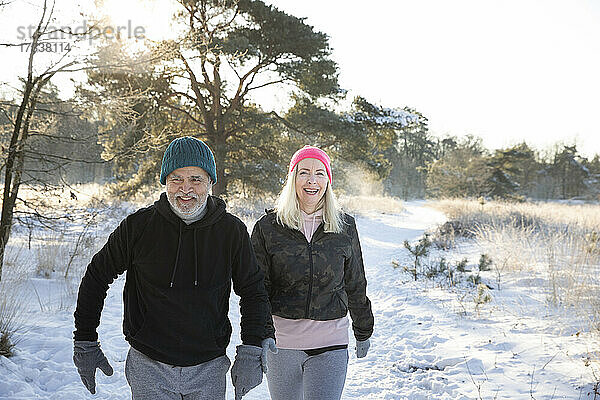Glückliches Paar  das zusammen auf Schnee spaziert