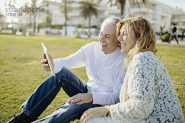 Glückliches reifes Paar macht Videoanruf durch digitale Tablette während des sonnigen Tages