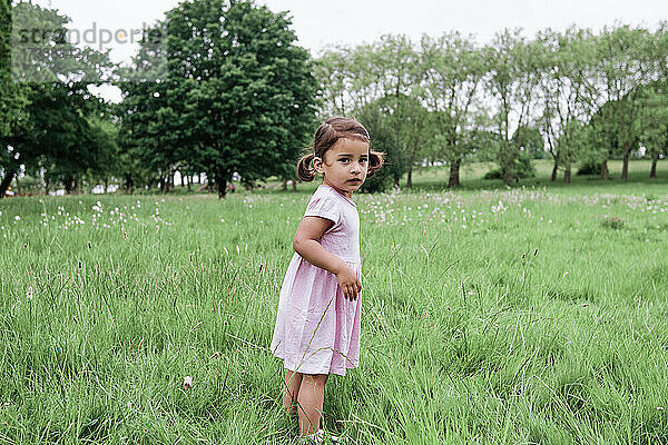 Unbeschwertes Mädchen steht auf Gras im Park