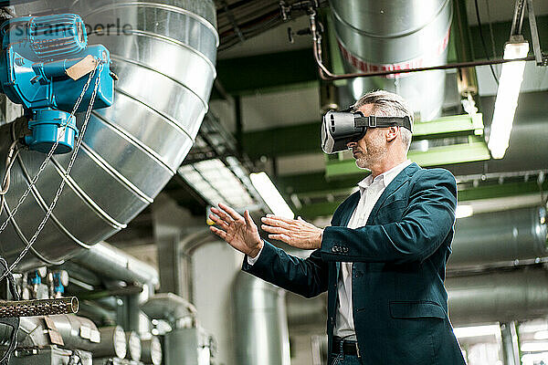 Geschäftsmann streckt die Hände aus  während er ein Virtual-Reality-Headset in der Industrie benutzt