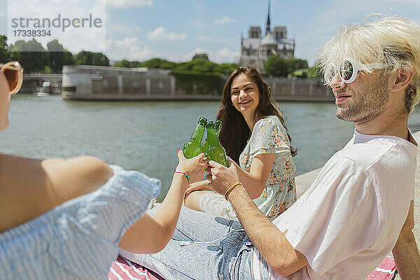 Lächelnde Freunde und Freundinnen stoßen an der Seine an