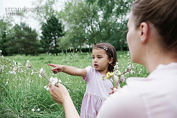 Mutter hält Blumen  während Tochter auf den Park zeigt
