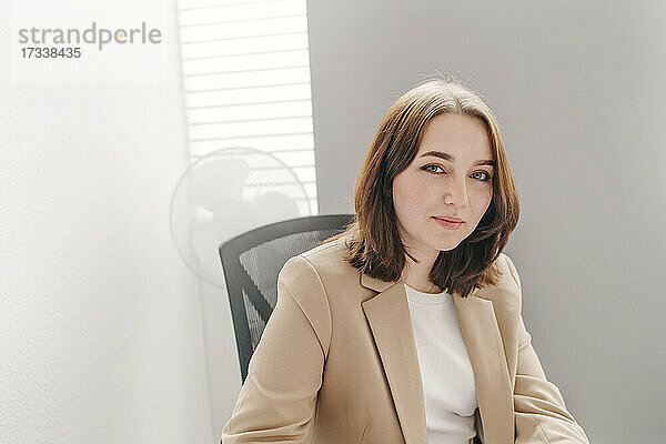 Junge Geschäftsfrau mit braunen Haaren sitzt im Büro