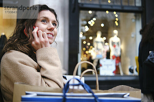 Frau schaut weg  während sie in einem Geschäft mit ihrem Smartphone telefoniert