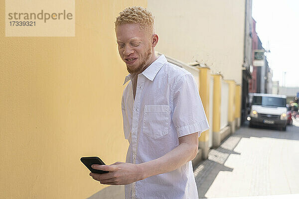 Deutschland  Köln  Albino-Mann im weißen Hemd hält Smartphone