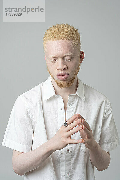 Studio-Porträt eines Albino-Mannes im weißen Hemd mit geschlossenen Augen