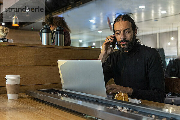 UK  London  Mann mit Laptop und Smartphone im Flughafencafé