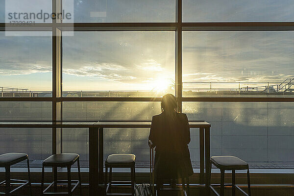 UK  London  Rückansicht einer Frau im Flughafenterminal bei Sonnenuntergang