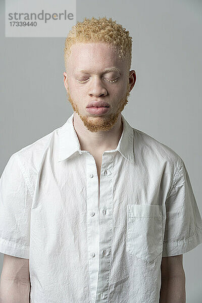 Studio-Porträt eines Albino-Mannes im weißen Hemd mit geschlossenen Augen