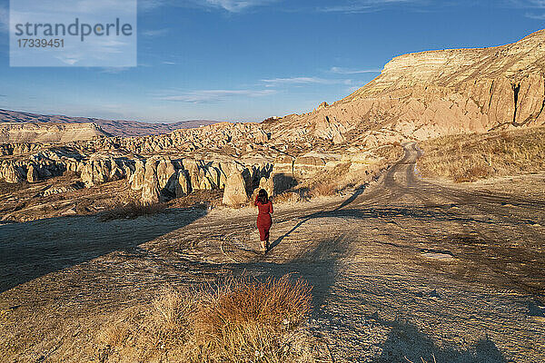 Türkei  Kappadokien  Rückansicht einer Frau in rotem Kleid in felsiger Landschaft