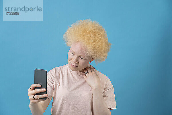 Studioaufnahme einer Albino-Frau mit Smartphone