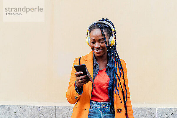 Italien  Mailand  Frau mit Kopfhörer und Smartphone im Freien