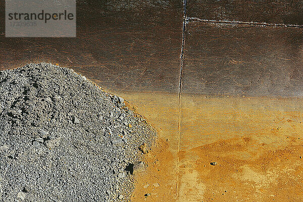Detail eines rostigen Metalltanks  Schotterhaufen im Vordergrund