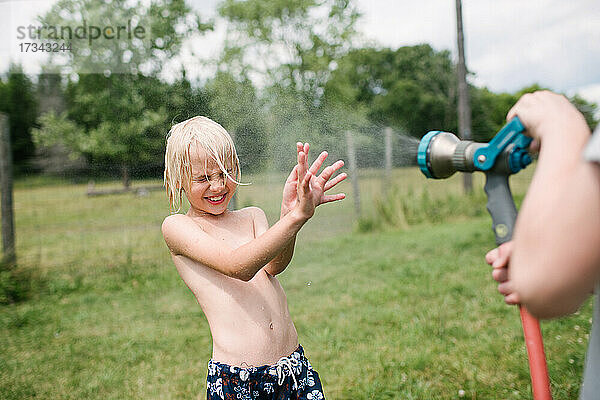 Kanada  Ontario  Kingston  Jungen (8-9  14-15) spielen mit Wasser aus einem Schlauch