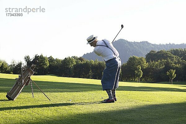 Älterer Mann mit Strohhut und Knickerbocker spielt Hickory Golf auf einem Golfplatz