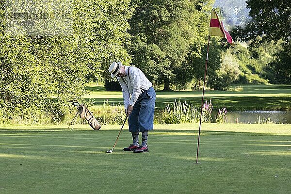 Älterer Mann mit Strohhut und Knickerbocker spielt Hickory Golf auf einem Golfplatz