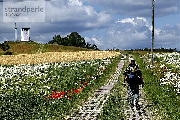 Mann mit Rucksack  Wanderer auf Kolonnenweg  Wanderweg durch Wiesen- und Feldflur  Lochplattenweg  Beobachtungsturm der Grenztruppen der DDR  Grenzwachturm  Grünes Band  Grenzweg  ehemalige deutsch-deutsche Grenze  Hermannsfeld  Gemeinde Rhönblick  L